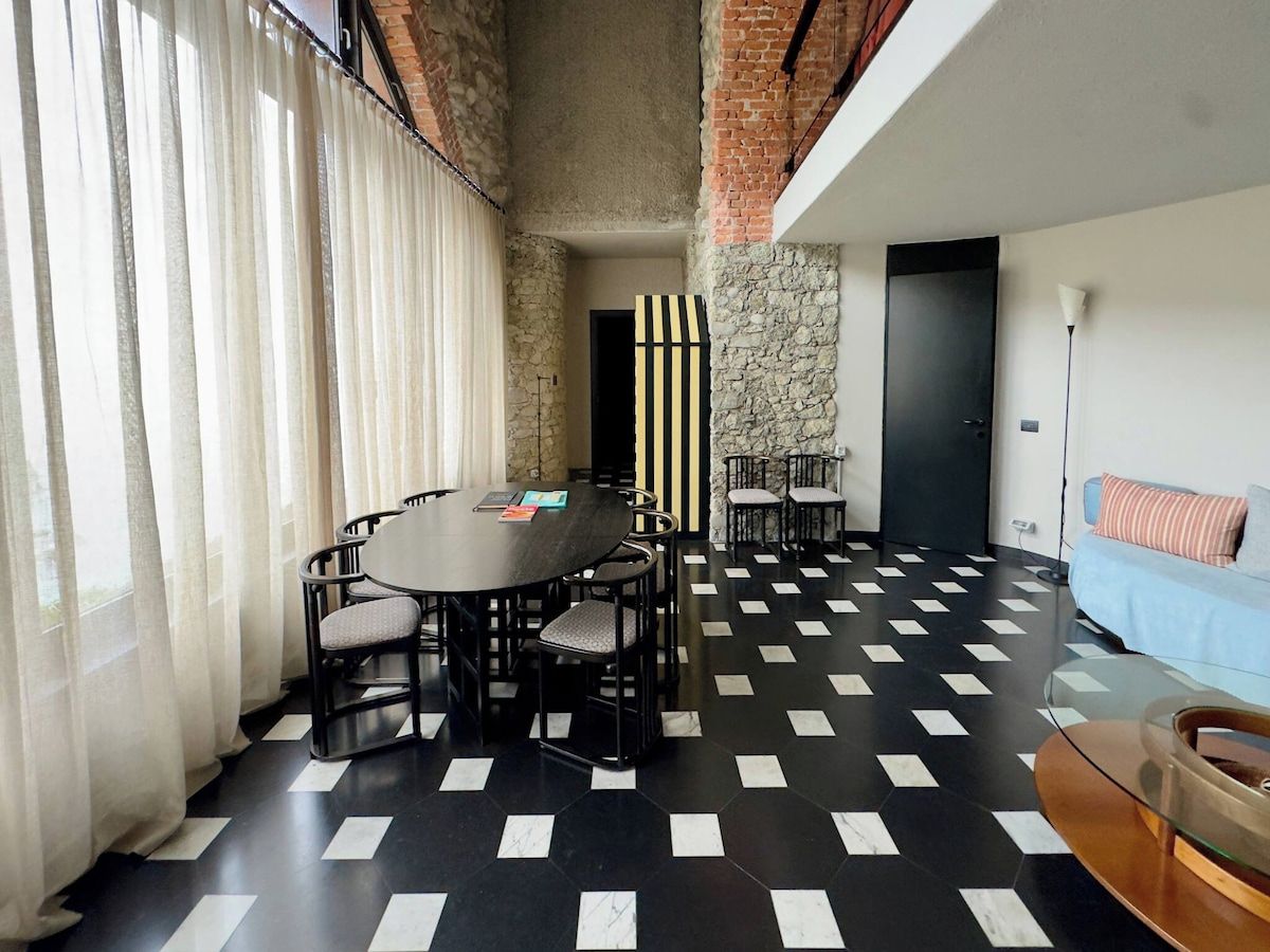 A room with a round table and chairs, a sofa, and a patterned floor.