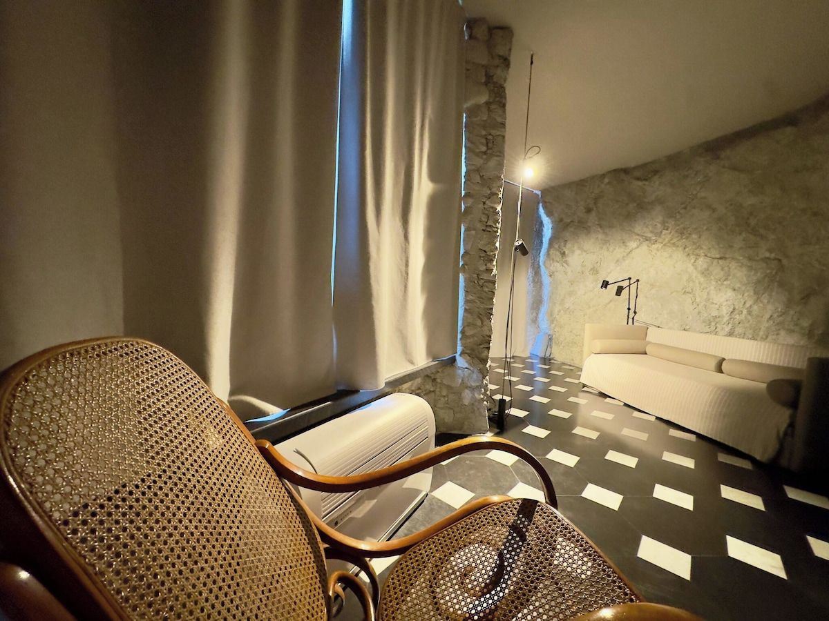 Ein modernes Zimmer mit einem Schachbrettmuster-Boden, einem Sofa, einem Sessel und einer Steinwand.