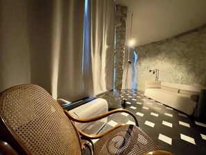Ein modernes Zimmer mit einem Schachbrettmuster-Boden, einem Sofa, einem Sessel und einer Steinwand.