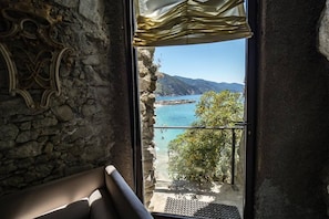 A stone wall, a bench, and a view of a coastal area with a clear sky.