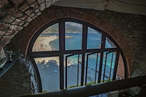 A stone arch window overlooking a beach.