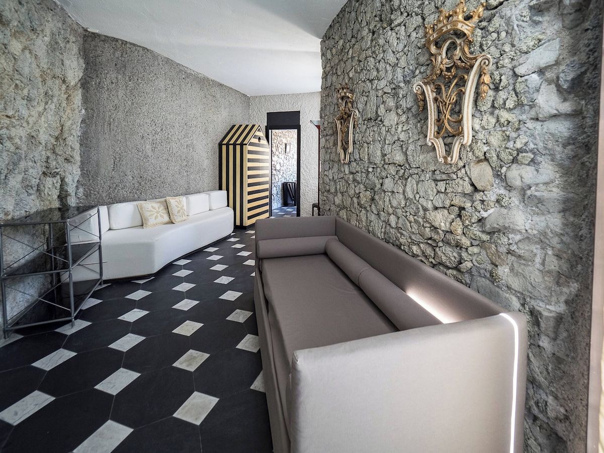 A modern interior with a stone wall, a white sofa, a bench, and a patterned floor.