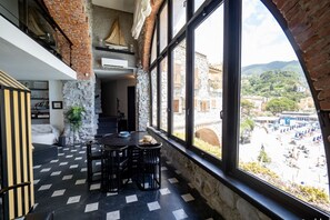A dining area with a checkered floor, a stone wall, and a view of a town through large windows.