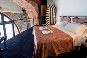 A hotel room with a bed, a view of a brick wall, and a staircase.