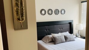 Een slaapkamer met een bed, nachtkastje, lamp en decoratieve wandkunst.