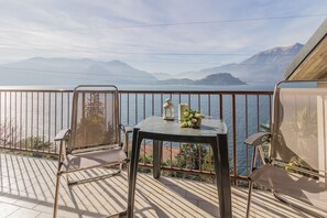 Ein Balkon mit Tisch und Stühlen mit Blick auf einen See und Berge.