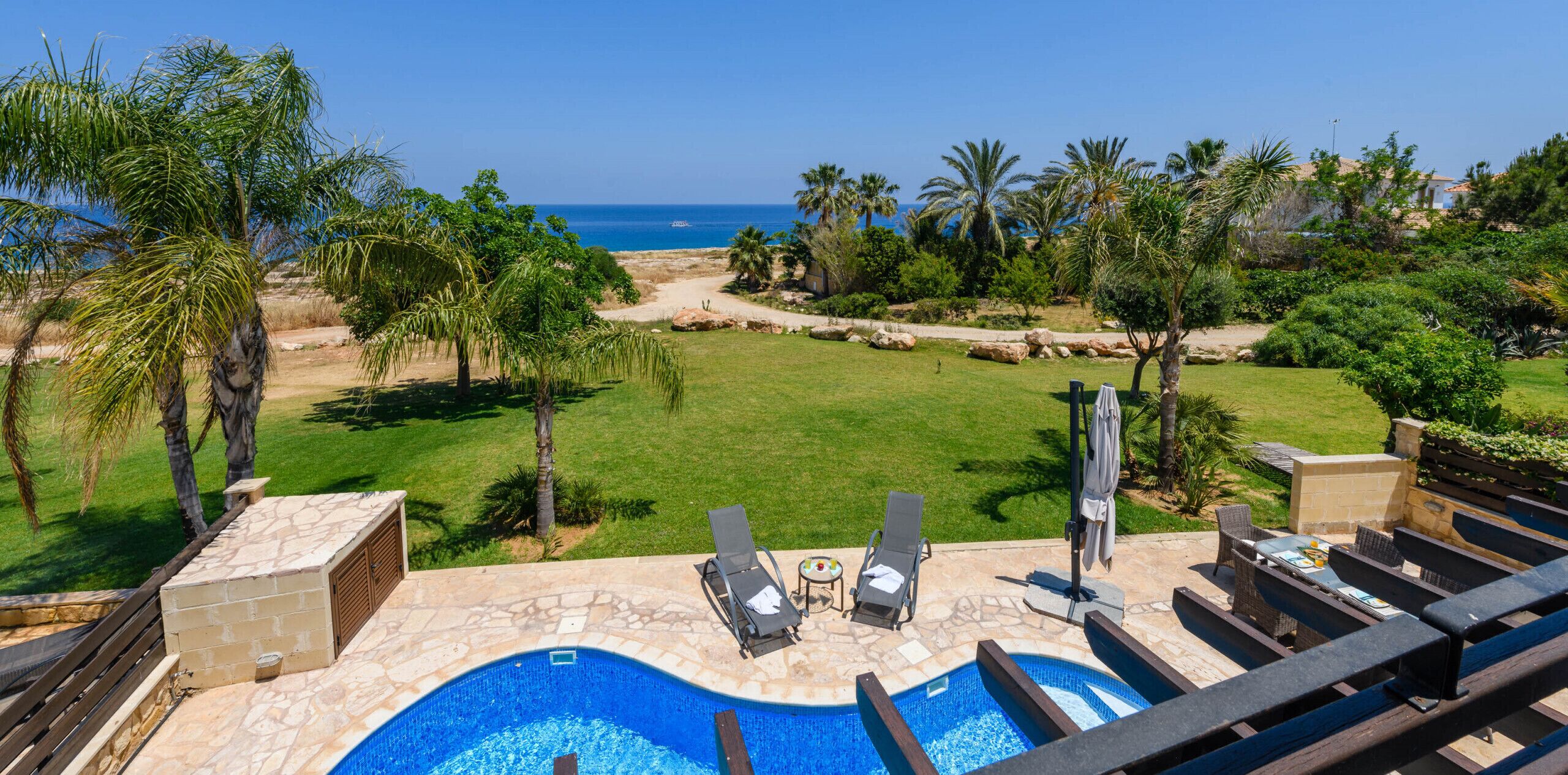 Un área de piscina con sillones de descanso y vistas al océano.