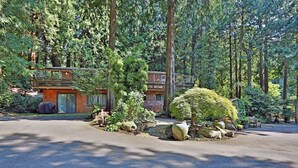 A two-story wooden cabin with a balcony, surrounded by dense forest. - House in the Woods [whole house] (Issaquah)