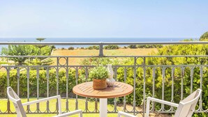 Een balkon met een ronde tafel, twee stoelen en een bloempot.