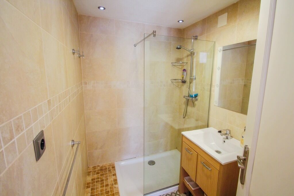 A bathroom with a glass-enclosed shower, a sink, and a mirror.