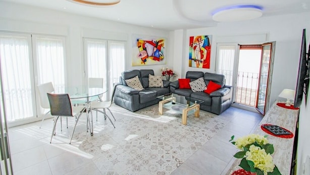 A modern living room with a glass dining table, two grey sofas with patterned cushions, and abstract paintings on the walls. - Judith - modern apartment in Moraira (Moraira)