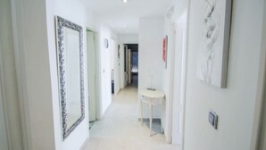 A hallway with a large mirror, a small table, and artwork on the walls. - Judith - modern apartment in Moraira (Moraira)