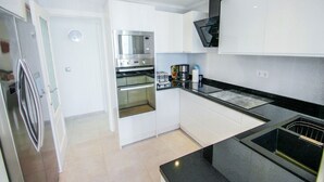 A modern kitchen with white cabinets, a built-in oven, a microwave, and a black countertop. - Judith - modern apartment in Moraira (Moraira)