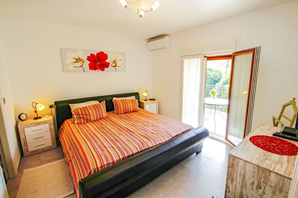 Une chambre à coucher comprenant un lit, des tables de chevet, une commode, un miroir et une vue sur l’extérieur.