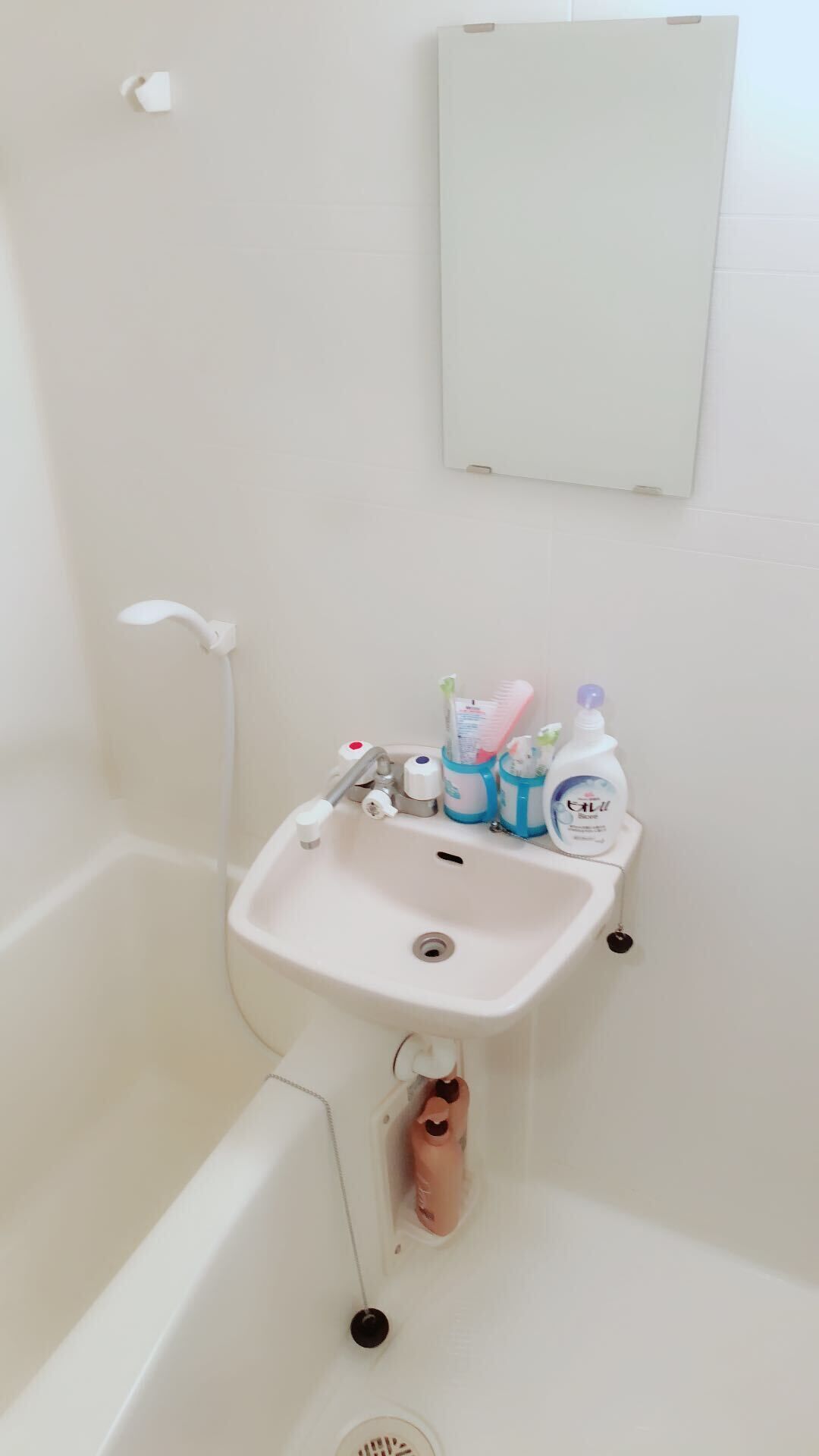 A bathroom with a white sink, toothbrushes, toothpaste, and a soap dispenser.