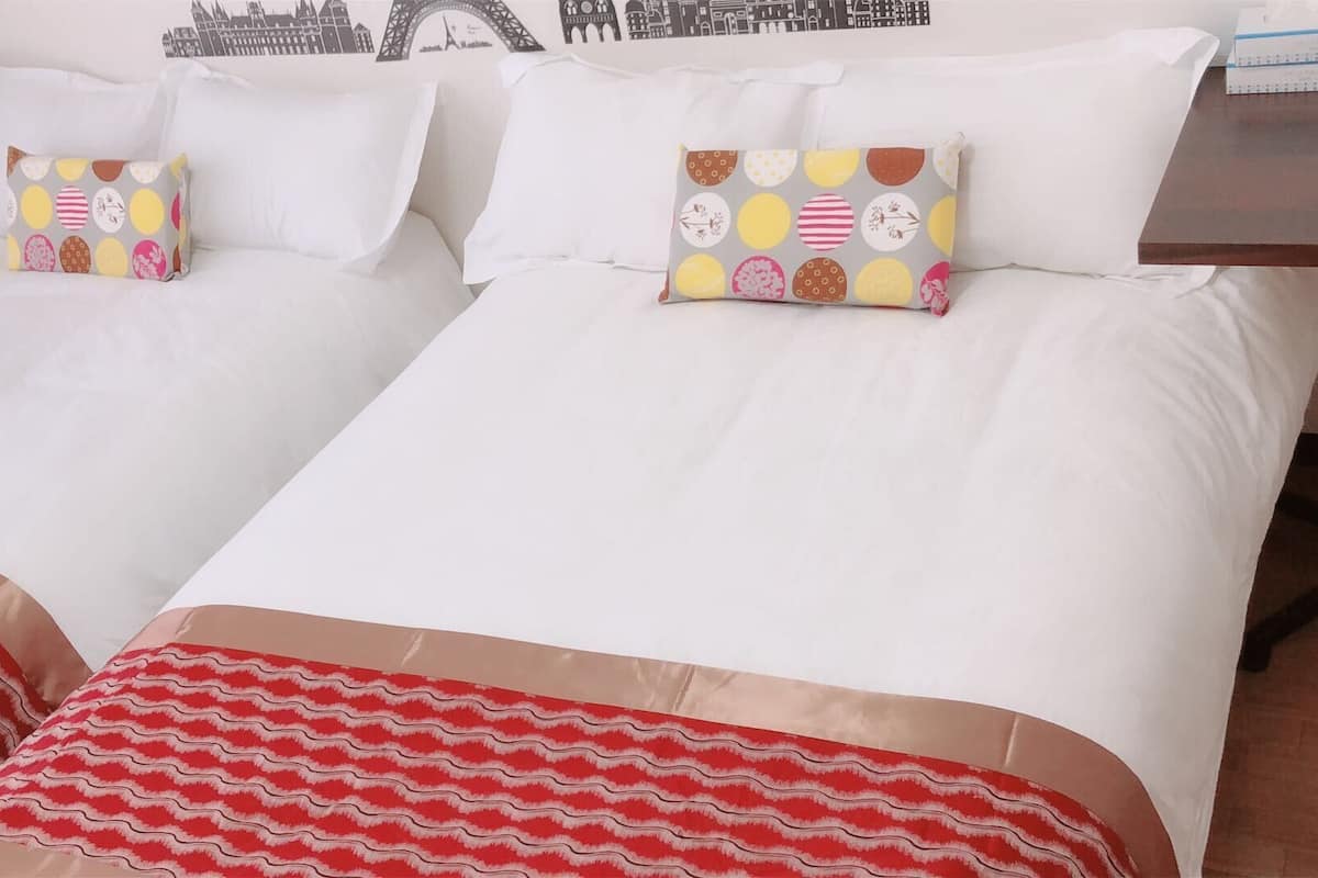 Una cama doble con ropa de cama blanca y dos almohadas decorativas con estampado de lunares.