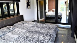 A bedroom with a bed, a wardrobe, and a sliding glass door leading to a balcony.