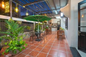 An indoor patio area with a green umbrella, terracotta tiles, and potted plants. - Old Lane Homestay (Da Nang)