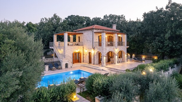 A two-story stone house with a swimming pool, outdoor seating, and a well-maintained garden. - Villa Melpomeni | in a Forest with Private Pool, Sea View, Gym & Home Cinema (Rethymno)