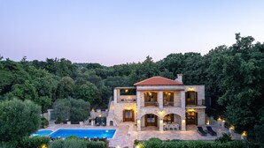 A two-story stone house with a swimming pool, surrounded by lush greenery. - Villa Melpomeni | in a Forest with Private Pool, Sea View, Gym & Home Cinema (Rethymno)