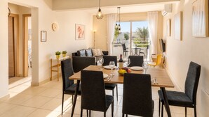 Comedor con mesa dispuesta para cuatro, sillas, sofá y balcón con vistas.