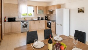 Una cocina moderna con lavadora, una mesa para dos personas y una botella de vino.