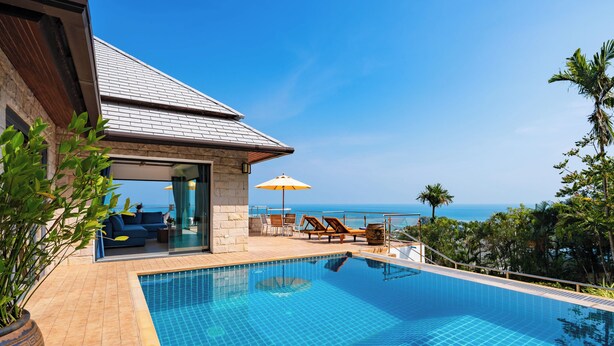 Ein moderner Poolbereich mit freiem Blick auf den Ozean, ein Steinhaus und eine Lounge mit Seeblick.