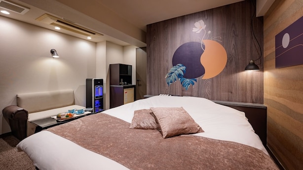 A hotel room with a large bed, a desk with a computer, a wall-mounted TV, and a decorative wall art piece. - HOTEL WILL BASE Tsurumi - Adults Only (Yokohama)