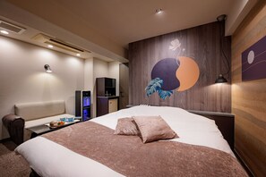 Habitación de hotel con una cama grande, un escritorio con computadora, un televisor montado en la pared y una obra de arte decorativa.
