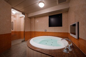 A modern bathroom with a large bathtub, a shower area, and a television mounted on the wall. - HOTEL WILL BASE Tsurumi - Adults Only (Yokohama)