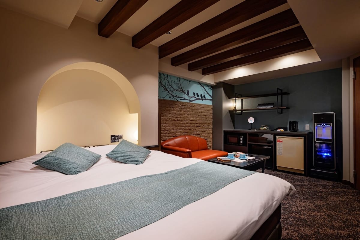 Une chambre d’hôtel équipée d’un lit, d’un bureau, d’une chaise, d’une petite kitchenette et d’un téléviseur.