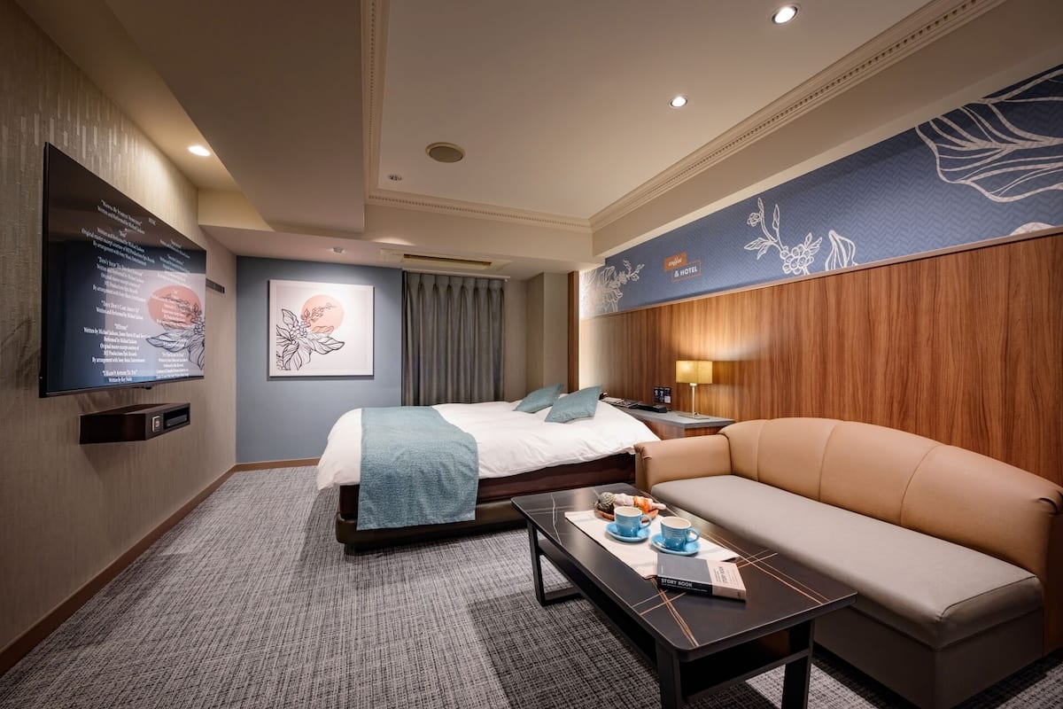 Une chambre d’hôtel équipée d’un lit, d’un canapé, d’une table basse et d’un téléviseur fixé au mur.