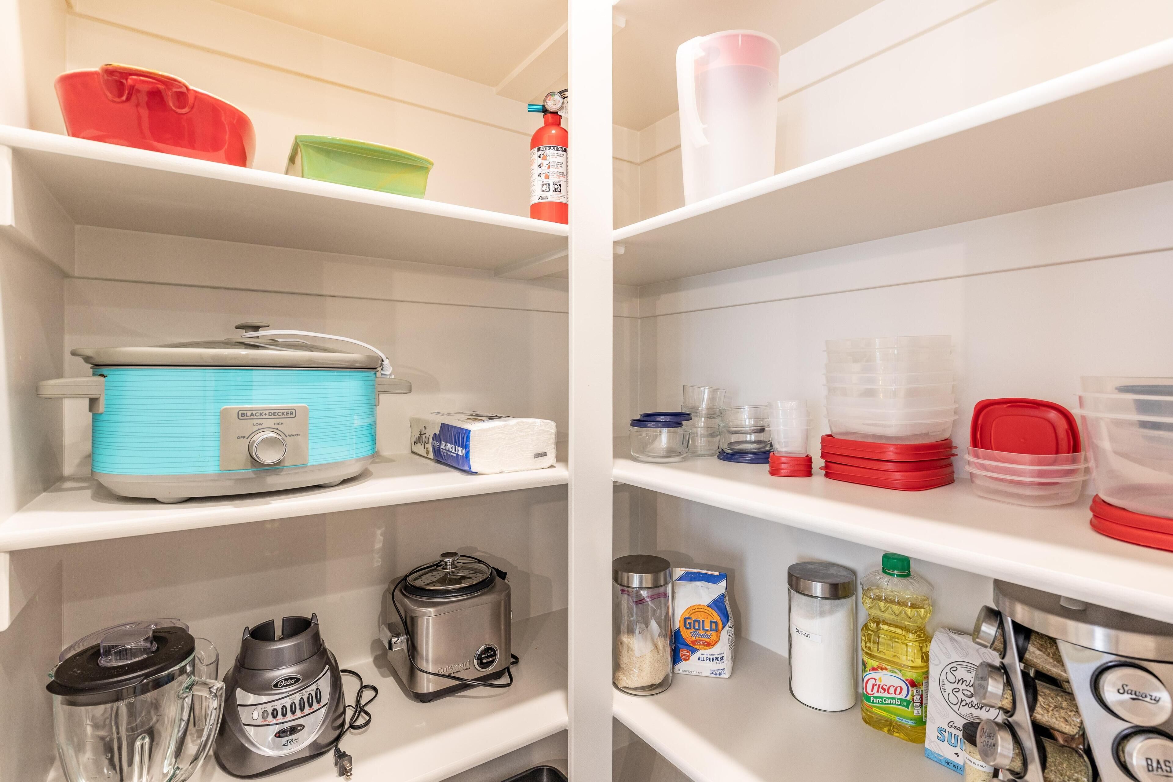 A kitchen with a blender, a coffee maker, a rice cooker, and various kitchen utensils on the counter.