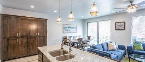 A modern kitchen with granite countertops, wooden cabinets, and pendant lighting.