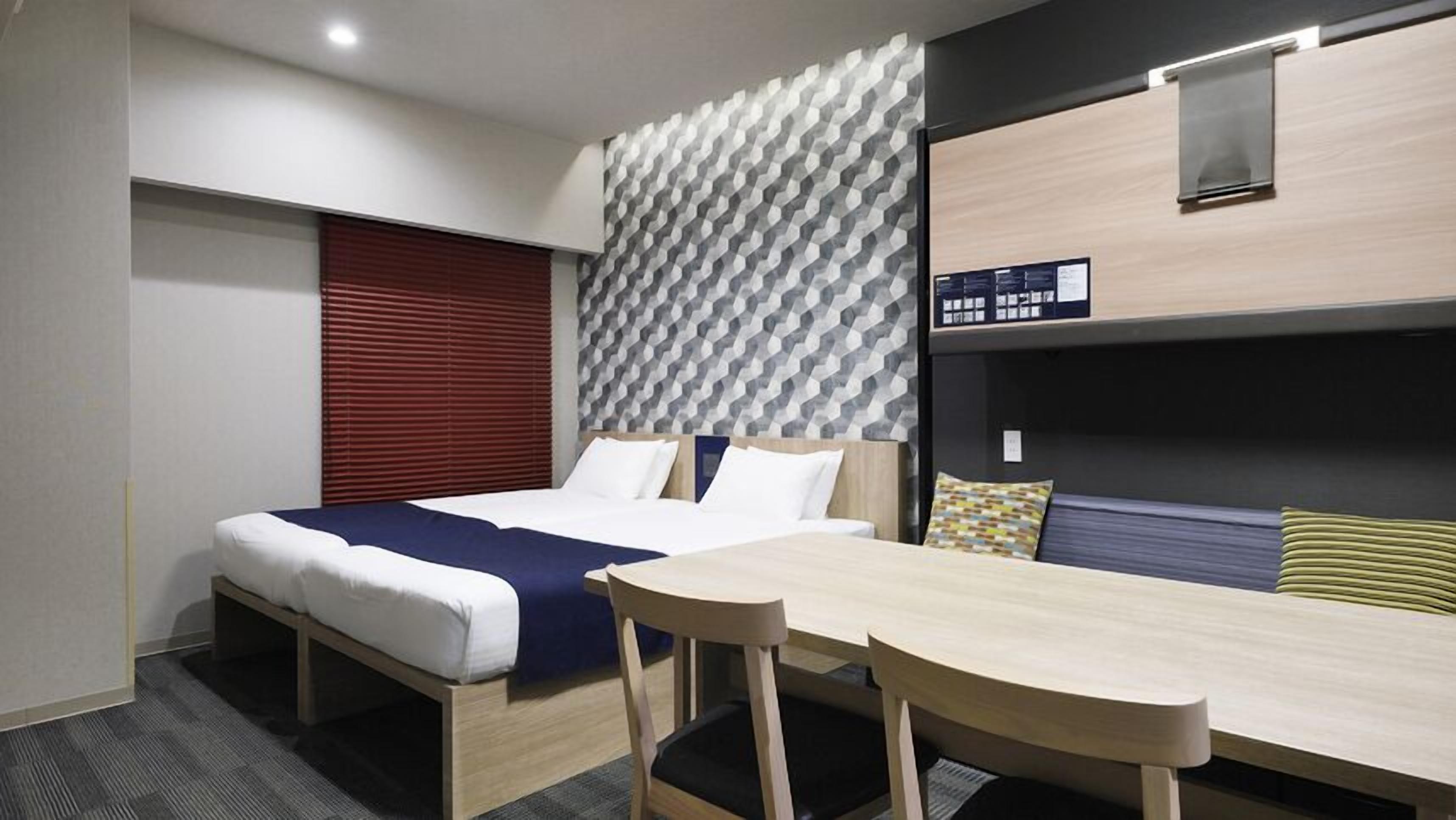 Une chambre d’hôtel avec un lit, un bureau et un lit superposé.