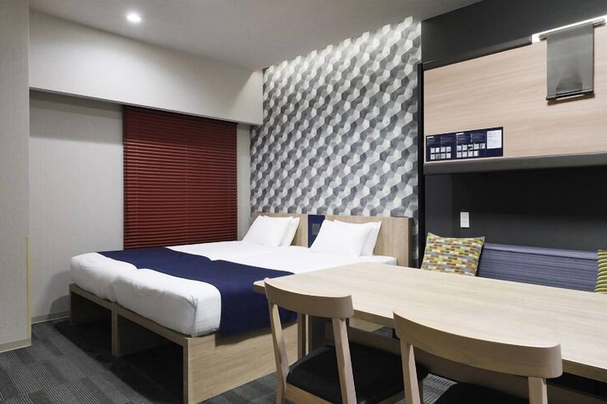 A hotel room with a bed, a desk, and a bunk bed.
