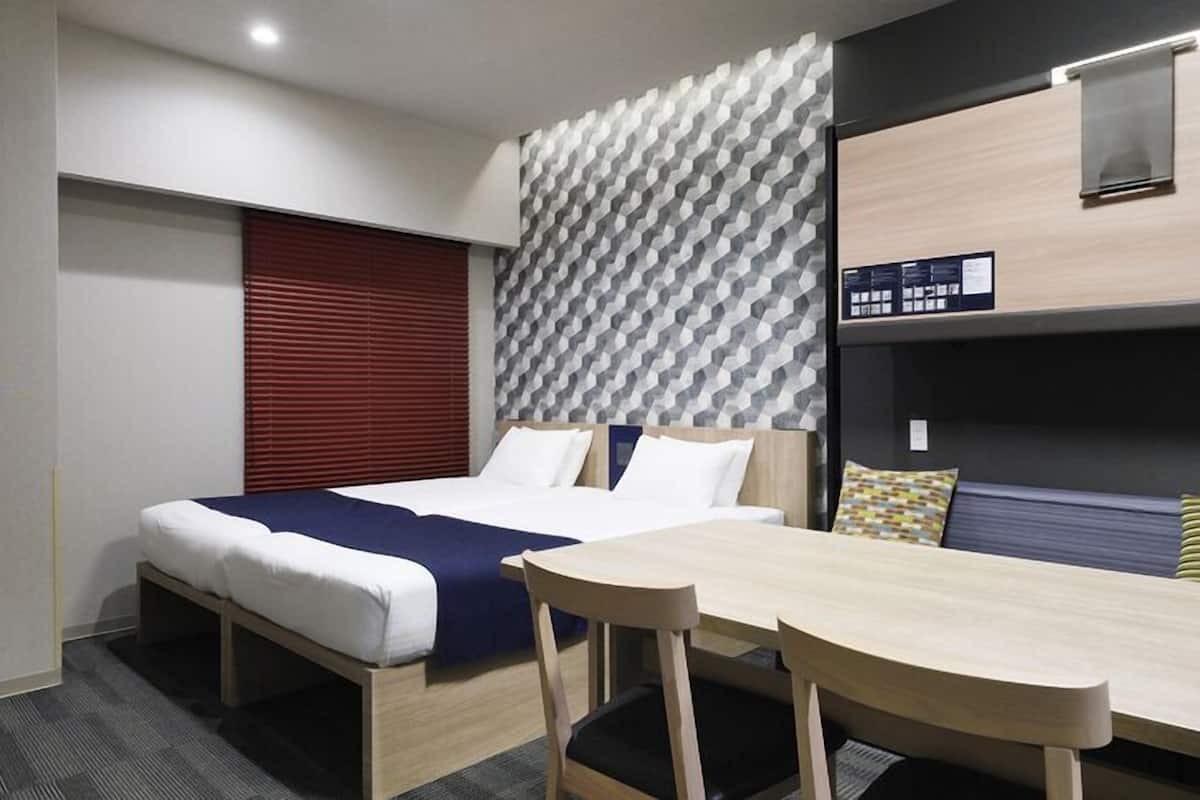 A hotel room with a bed, a desk, and a bunk bed.