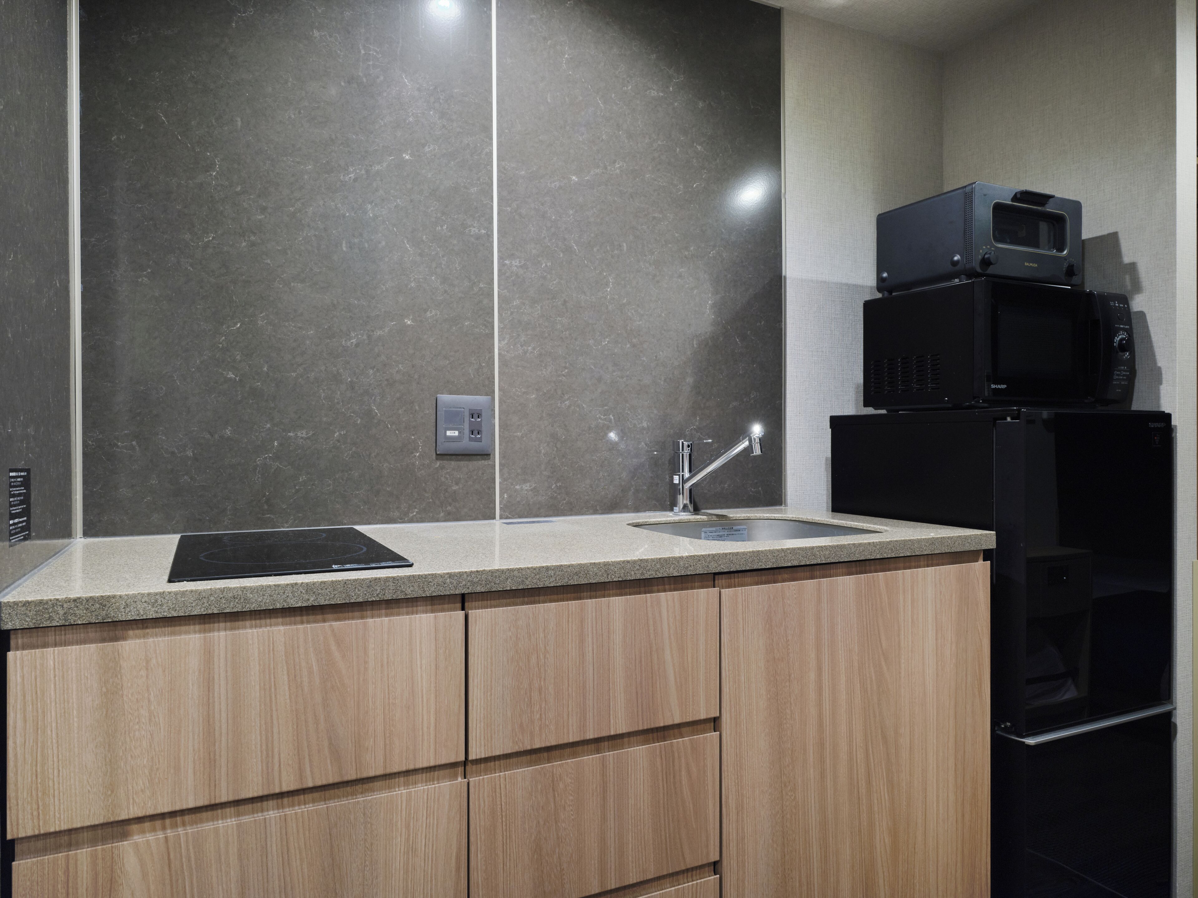 A modern kitchen with a granite countertop, a stainless steel sink, and a built-in microwave.