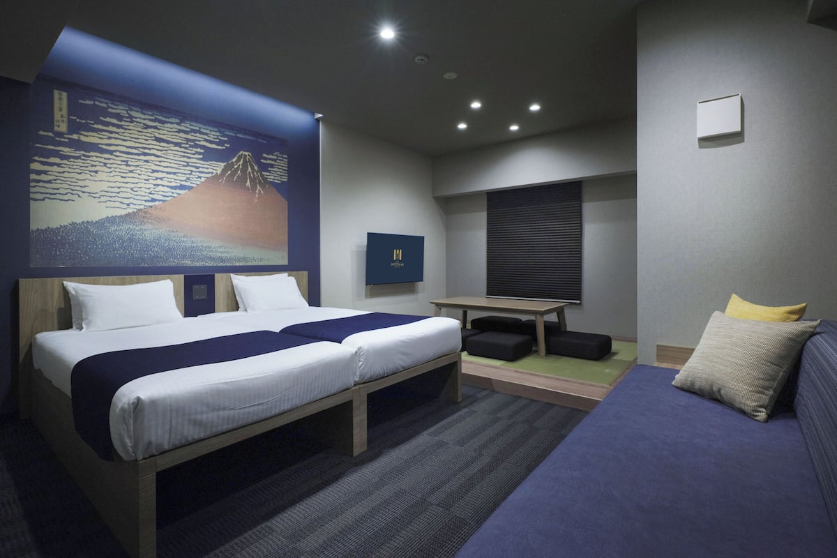 A modern hotel room with a large bed, a desk, and a sofa.