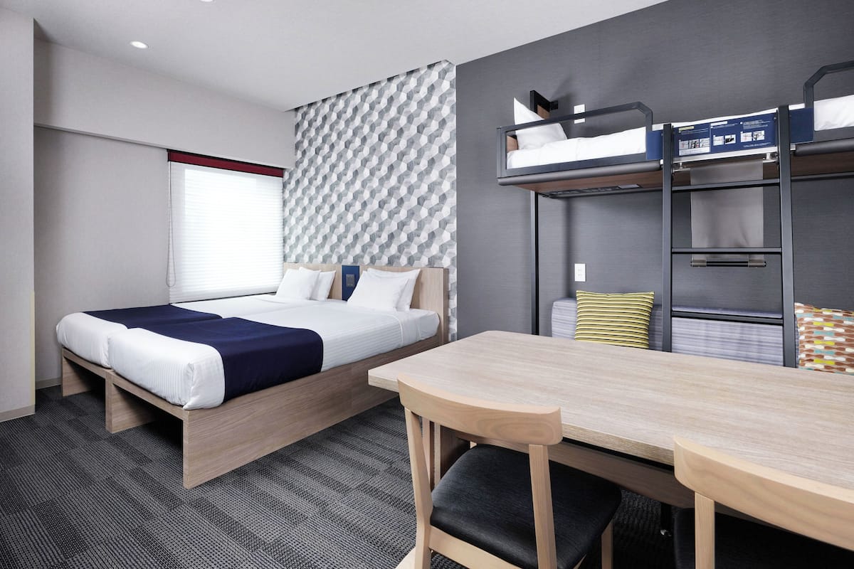 A hotel room with a bunk bed, a desk, and a chair.