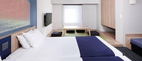 A modern hotel room with a large bed, a small table, a TV, and a painting of a mountain.