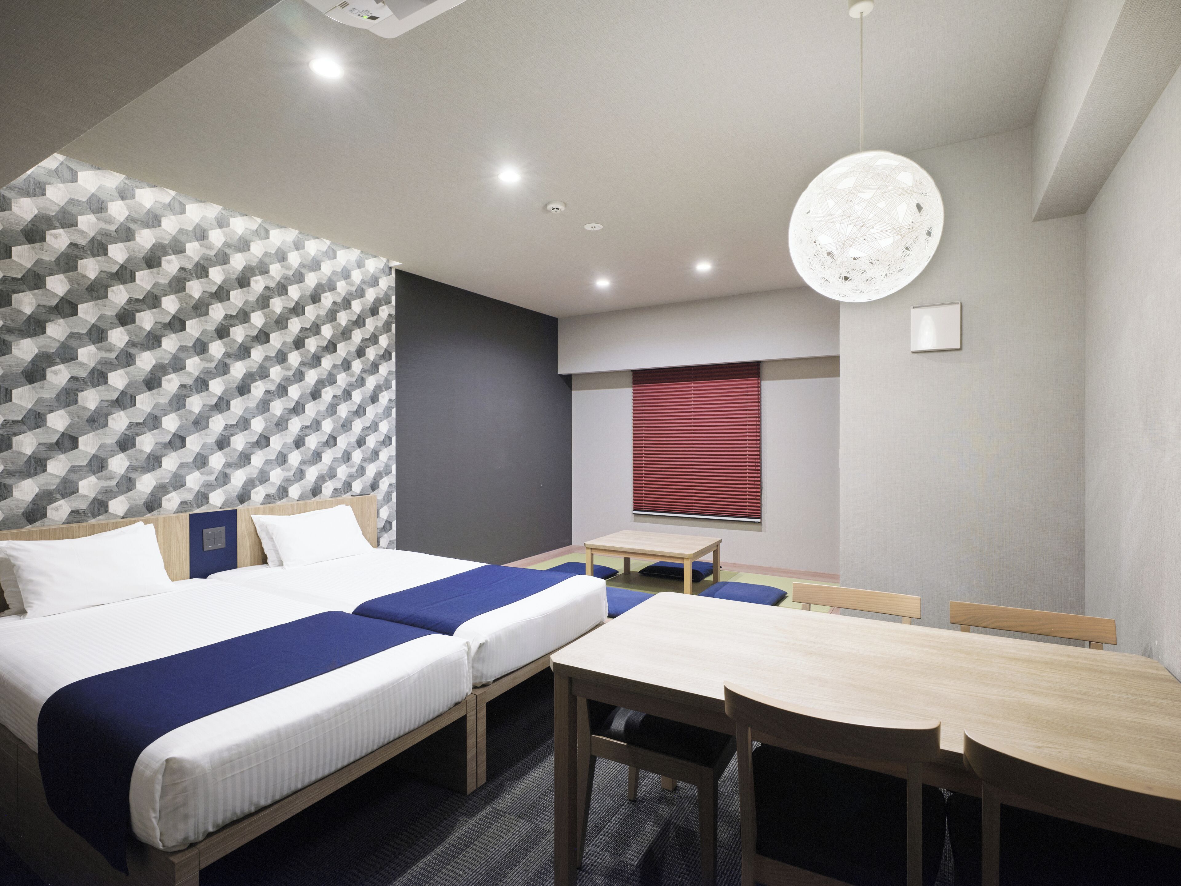 Une chambre d’hôtel moderne avec un grand lit, une table à manger et un mur orné d’un motif géométrique.