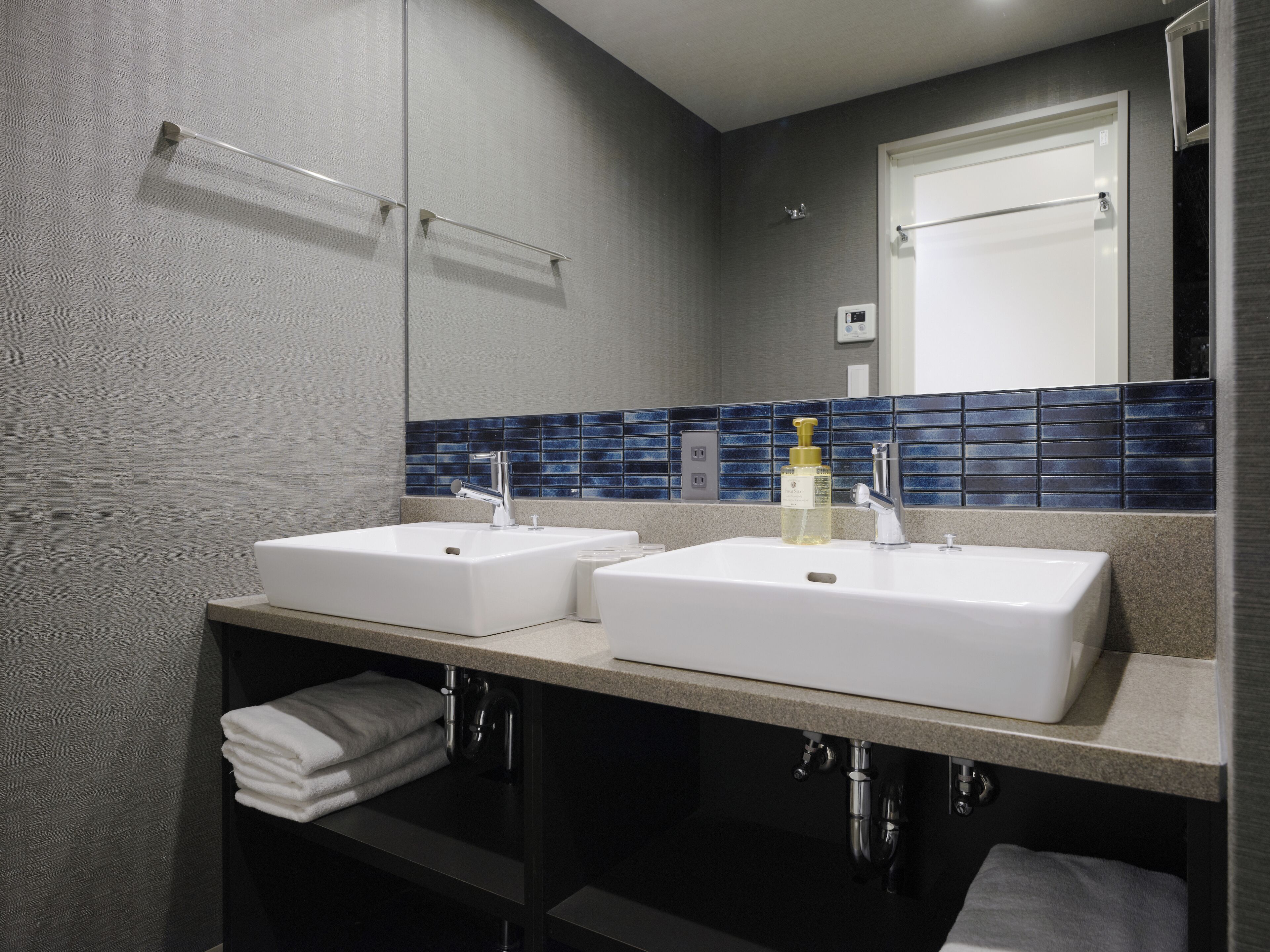 A modern bathroom with two sinks, a towel rack, and a mirror.