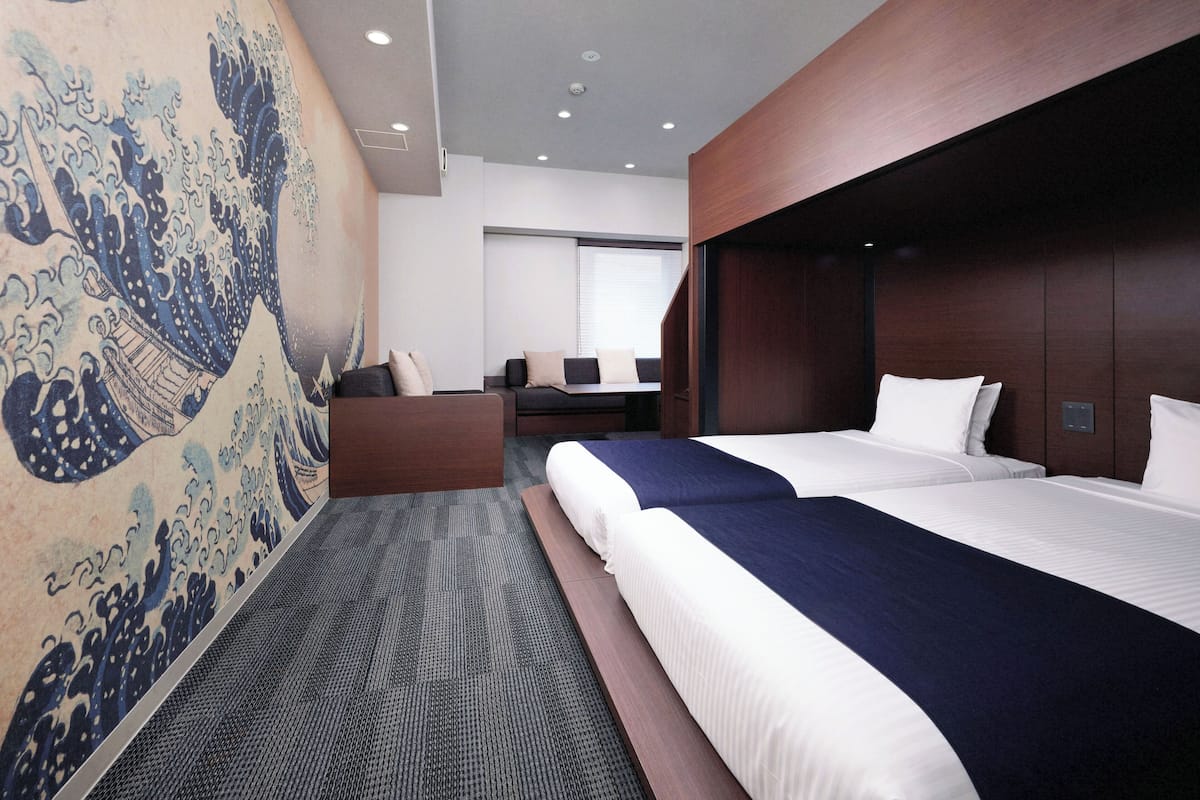 A modern hotel room with a large bed, a sofa, and a wall mural.