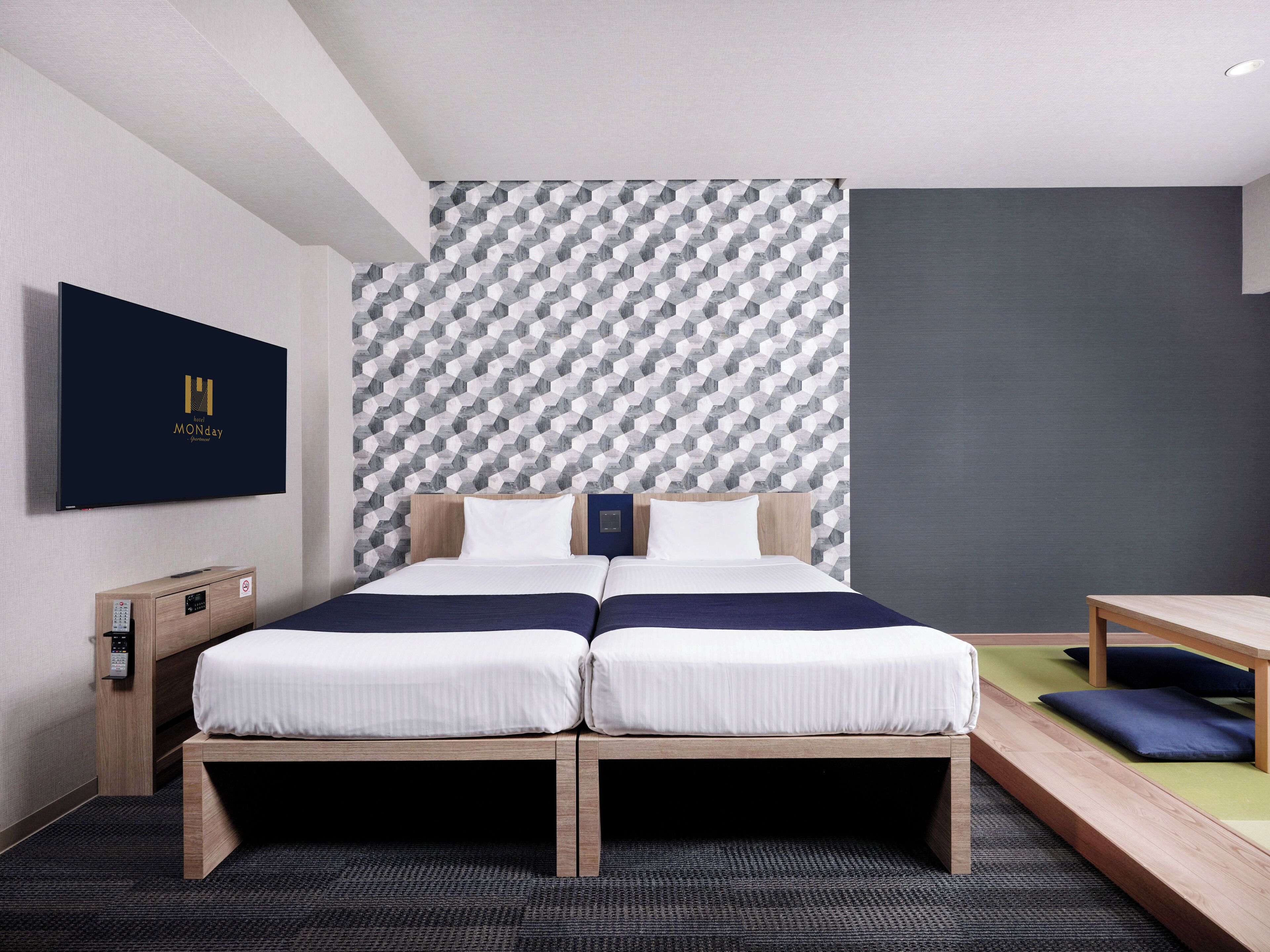 A modern hotel room with a bed, a desk, and a TV.