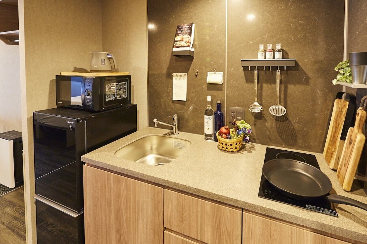 A compact kitchen with a microwave, sink, and induction cooktop.