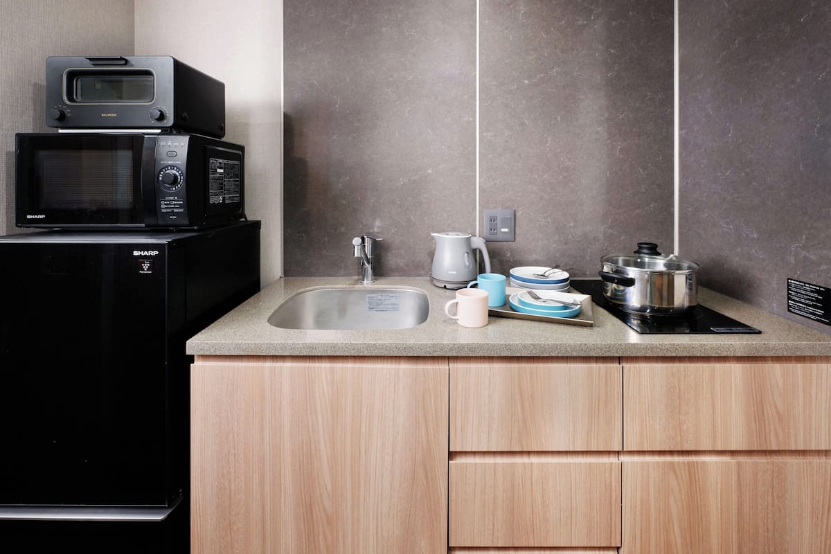 A kitchen with a microwave, coffee maker, sink, and a pot on the counter.