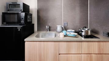 Una cocina con microondas, cafetera, lavabo y una olla sobre la encimera.