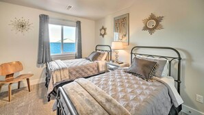 A bedroom with two beds, a wooden chair, a window with curtains, and decorative wall art. - Quiet Home by Dtwn Livingston: Hike, Fish & Ski! (Livingston)