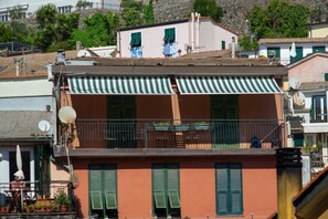 Ein Gebäude mit Balkon, grünen Fensterläden und einer Satellitenschüssel.